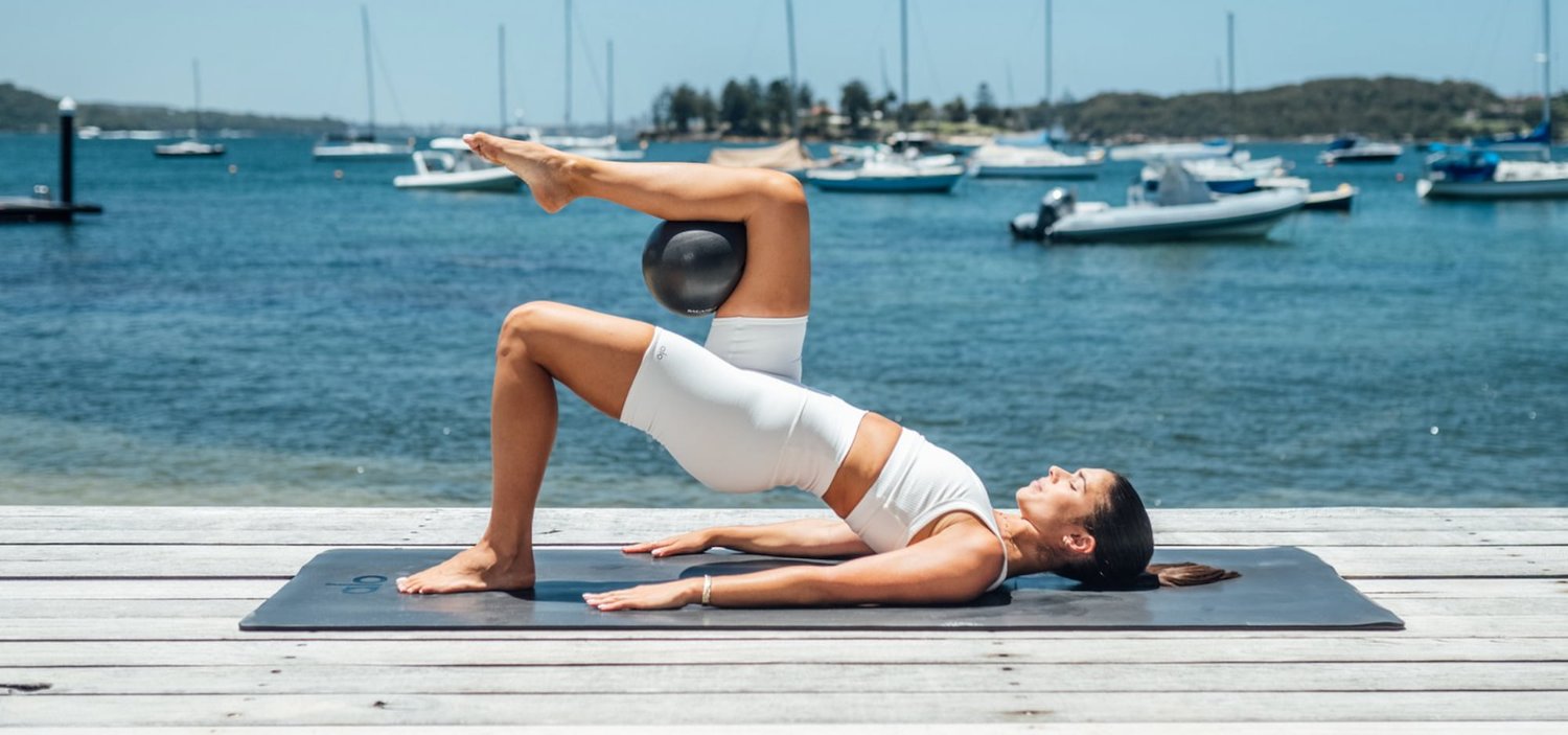 A person performing a Pilates exercise using a Pilates ball